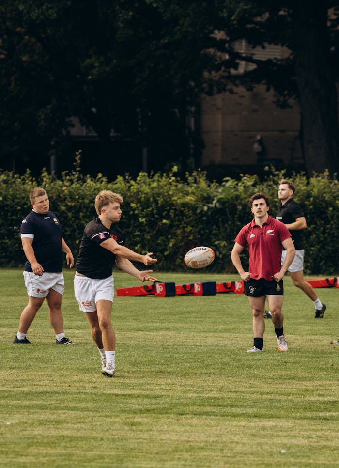 Energetic group of young men playing rugby in a Dublin park surrounded by greenery.